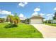 Tan house with a large grassy yard, palm tree, and a two-car garage at 20222 Banner Ave, Port Charlotte, FL 33952