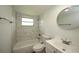Updated bathroom with a white vanity, bathtub, and marble-look tile at 20222 Banner Ave, Port Charlotte, FL 33952