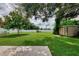 Large backyard with lush green grass, storage shed, and shade tree at 6701 Elmwood Rd, North Port, FL 34287