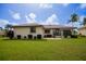 Single-Gathering home's backyard features a covered patio, lush lawn, and tropical landscaping at 442 Macedonia Dr, Punta Gorda, FL 33950