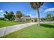 Ranch-style home with circular driveway, lush lawn, and palm trees at 4041 Michel Tree St, Port Charlotte, FL 33948