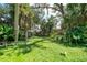 Large backyard with a grassy area, tropical plants and a wooden bench at 4041 Michel Tree St, Port Charlotte, FL 33948