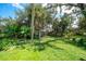 Large backyard with a grassy area, tropical plants and a wooden bench at 4041 Michel Tree St, Port Charlotte, FL 33948