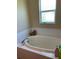 Bathroom with an oval tub, tiled walls, and a window at 2106 Switzerland Rd, North Port, FL 34288