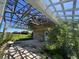 Brick home with damaged covered patio, overgrown landscaping, and a view of open land at 31840 Washington Loop Rd, Punta Gorda, FL 33982