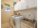 Bright laundry room with white cabinets, a utility sink, and washer/dryer at 32121 Washington Loop Rd, Punta Gorda, FL 33982