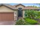 House exterior featuring a two-car garage and well-manicured landscaping at 1596 Hyssop Loop, North Port, FL 34289