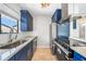 Modern kitchen featuring stainless steel appliances, granite countertops, and custom blue cabinetry at 1001 W Marion Ave # 14, Punta Gorda, FL 33950