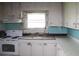 This dated kitchen features white cabinets, turquoise tile, and needs renovation at 702 W Olympia Ave, Punta Gorda, FL 33950