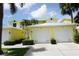 Exterior of yellow condominium building featuring white garage doors, lush landscaping, and a well-maintained driveway at 2000 Bal Harbor Blvd # 1012, Punta Gorda, FL 33950
