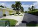 Long street view of yellow condominiums featuring white garage doors, green lawns, and tropical palm trees at 2000 Bal Harbor Blvd # 1012, Punta Gorda, FL 33950