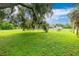 Large backyard with lush grass and mature oak tree at 335 Kenova St, Port Charlotte, FL 33954