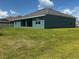 Back exterior view of single story home with well-maintained lawn, blue paint, and dark roof at 10133 Audrey St, Port Charlotte, FL 33981