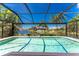 Screened-in pool with lovely lake views and blue skies above lush, green tropical landscaping at 17085 Thyme Ct, Punta Gorda, FL 33955