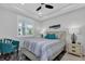 Bright bedroom with large window, tray ceiling, ceiling fan, stylish decor, and wood-look flooring at 1425 Park Beach Cir # 127, Punta Gorda, FL 33950