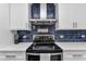 Close-up of the kitchen featuring a black oven range, white countertops, and blue tiled backsplash at 1425 Park Beach Cir # 127, Punta Gorda, FL 33950