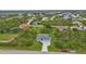 Aerial view of a light green house with a three-car garage, a large yard, and a neighborhood background at 14516 San Domingo Blvd, Port Charlotte, FL 33981
