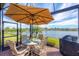 Relaxing covered patio with a dining table, grill, and serene lake views at 1289 Ballota Ln, North Port, FL 34289