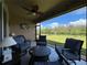 Enjoy the peaceful view from this screened-in patio featuring comfortable blue chairs and a ceiling fan at 25168 E Lenox Cir, Punta Gorda, FL 33950