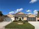Two-car garage home with a tan exterior and landscaping at 25168 E Lenox Cir, Punta Gorda, FL 33950