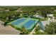 Aerial view of community tennis courts and clubhouse amidst lush greenery and residential buildings at 19375 Water Oak Dr # 302, Port Charlotte, FL 33948