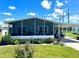 Mobile home exterior with covered porch, landscaping, and golf cart at 743 Tangerine Woods Blvd, Englewood, FL 34223
