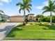 Inviting home featuring lush landscaping, a three-car garage, and a charming front entrance at 15378 Taurus Cir, Port Charlotte, FL 33981