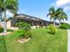 Backyard view of house with screened patio and landscaping at 15378 Taurus Cir, Port Charlotte, FL 33981