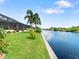 Backyard view of canal, lush grass, and palm trees at 15378 Taurus Cir, Port Charlotte, FL 33981