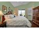 Main bedroom with king bed, wood floors, and access to backyard patio at 3589 Pennyroyal Rd, Port Charlotte, FL 33953