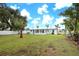 Spacious backyard with grassy lawn, palm tree, and white fence at 2513 Elkcam Blvd, Port Charlotte, FL 33952