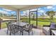 Inviting screened-in patio with a dining table, chairs, and a serene view of the green backyard at 16390 Bridle Ridge St, Port Charlotte, FL 33953