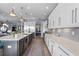 Open kitchen boasts white cabinets, stainless appliances, an island with bar seating, and a view of the living area at 5241 Grand Palmetto Way, North Port, FL 34291