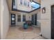 Secluded outdoor patio area, featuring neutral stonework, a decorative plant, and dark-framed windows at 5241 Grand Palmetto Way, North Port, FL 34291