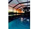 Screened-in pool reflecting a stunning sunset with water views at 5241 Grand Palmetto Way, North Port, FL 34291