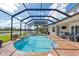 Covered pool and brick patio, with a serene view of the lake and lush greenery at 5241 Grand Palmetto Way, North Port, FL 34291