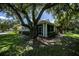 Backyard features a screened porch and lush landscaping under large trees at 1274 White Oak Trl, Port Charlotte, FL 33948
