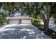 Three-car garage with American flag and lush landscaping at 1274 White Oak Trl, Port Charlotte, FL 33948