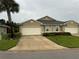 Tan two-car garage home with landscaping and a palm tree at 7633 W Lenox Cir, Punta Gorda, FL 33950
