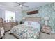Bedroom with wood platform bed, leafy wallpaper and wicker chair at 3228 Purple Martin Dr # 113, Punta Gorda, FL 33950
