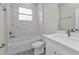 Bright bathroom with white marble tiled walls, updated vanity, and tub at 4255 Oak Terrace Cir, Port Charlotte, FL 33953