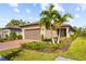 Tan house with brown garage door, palm tree, and landscaped yard at 1384 Raspberry Dr, North Port, FL 34289