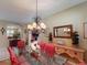 Bright dining room with glass-top table, red chairs and sideboard at 5291 Laurel Oak Ct, North Port, FL 34287