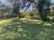 Large grassy backyard with mature trees and a screened patio at 2439 Margaret Ln, North Port, FL 34286