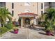 Condo building entrance with covered seating area, lush landscaping, and inviting atmosphere at 25188 Marion Ave # B304, Punta Gorda, FL 33950