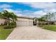 Tan house with two-car garage, paver driveway, and palm trees at 24211 Savory Ln, Punta Gorda, FL 33955