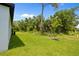 Large, verdant backyard featuring young trees and natural wooded area beyond the lawn at 2404 Hanford Ln, North Port, FL 34288