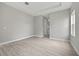 This is a bright bedroom with grey walls and wood-look flooring, featuring a bathroom and windows with lush outside views at 2404 Hanford Ln, North Port, FL 34288