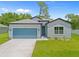Charming single-story home featuring a light blue exterior, a well-kept lawn and a blue garage door at 2404 Hanford Ln, North Port, FL 34288