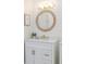 Bathroom vanity featuring white cabinets, marble countertop, and a decorative round mirror at 956 Harbor Town Dr, Venice, FL 34292